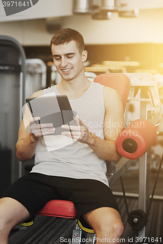 Image of smiling young man with tablet pc computer in gym