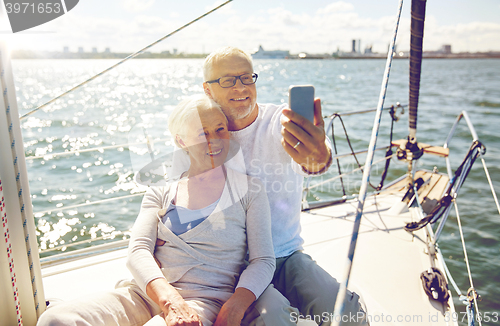 Image of seniors with smartphone taking selfie on yacht