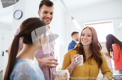 Image of happy creative team drinking coffee at office