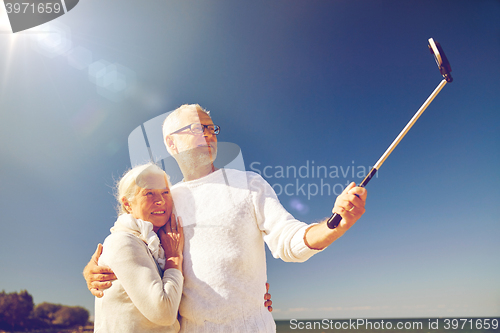 Image of seniors with smartphone taking selfie on beach