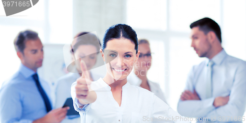 Image of businesswoman in office showing thumbs up