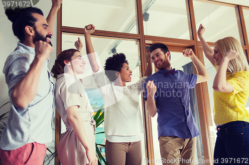 Image of happy creative team celebrating victory in office