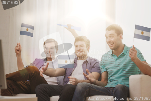 Image of happy male friends with flags and vuvuzela