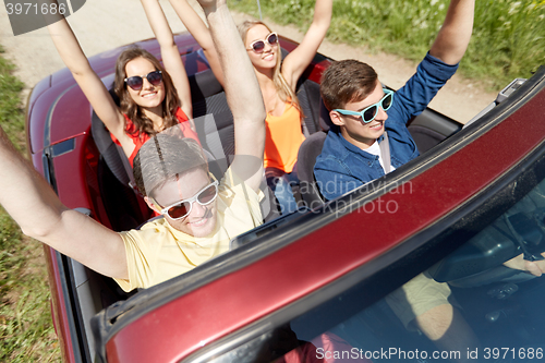 Image of happy friends driving in cabriolet car at country