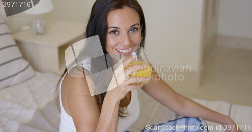 Image of Smiling healthy young woman drinking orange juice