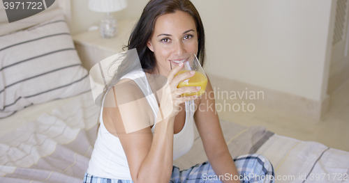 Image of Smiling healthy young woman drinking orange juice