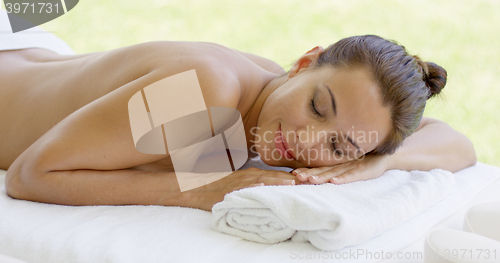 Image of Woman relaxing on spa table on outdoor patio