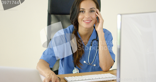 Image of Young female physician places one hand on her face