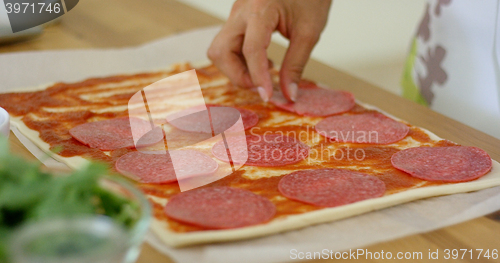 Image of Woman making a homemade salami and mushroom pizza