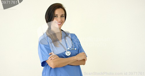 Image of Woman in scrubs crosses arms and smiles at camera