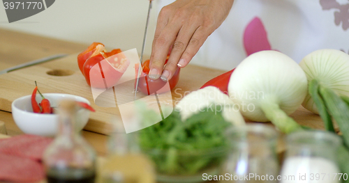 Image of Housewife chopping a fresh red bell pepper