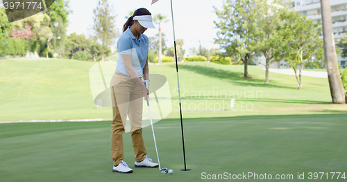 Image of Woman golfer about to sink her putt