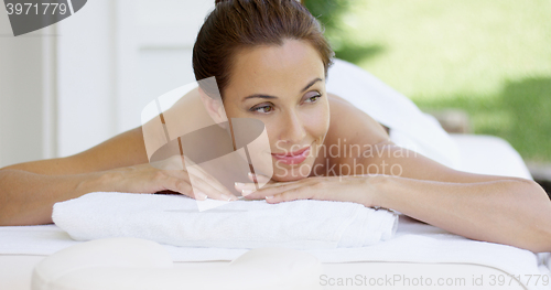 Image of Curious woman on spa table wrapped in white towels