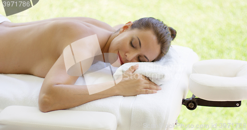 Image of Disrobed woman lays belly down on table