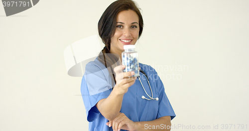 Image of Young brown haired doctor in scrubs holds bottle