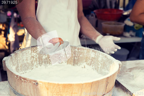 Image of close up of cook hands with meatball and flour