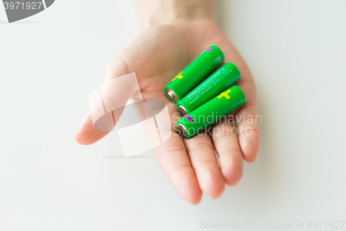 Image of close up of hand holding green alkaline batteries