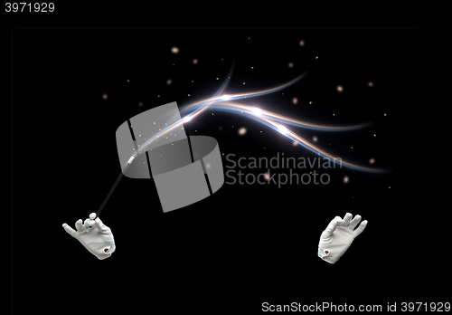 Image of magician hands with magic wand showing trick