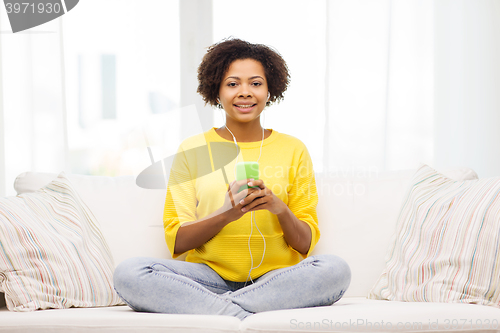 Image of happy african woman with smartphone and earphones