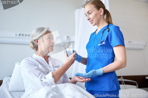 Image of nurse giving medicine to senior woman at hospital