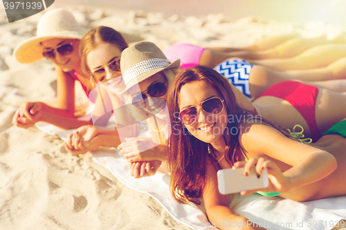 Image of group of smiling women with smartphone on beach