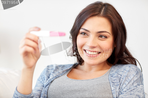 Image of happy woman looking at home pregnancy test