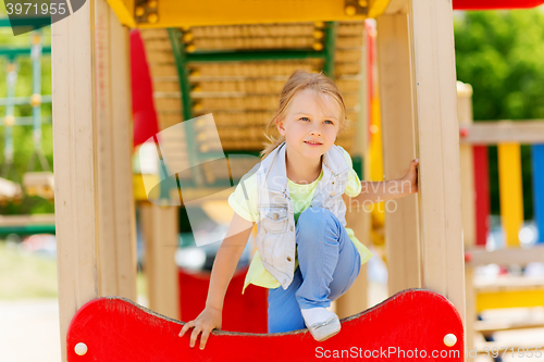 Image of happy little girl climbing on children playground