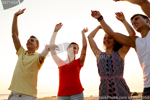 Image of smiling friends dancing on summer beach