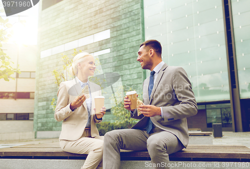 Image of smiling businessmen with paper cups outdoors