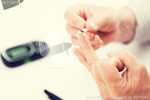 Image of senior woman with glucometer checking blood sugar