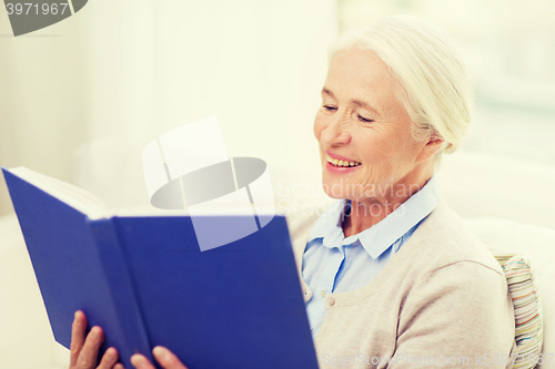 Image of happy smiling senior woman reading book at home