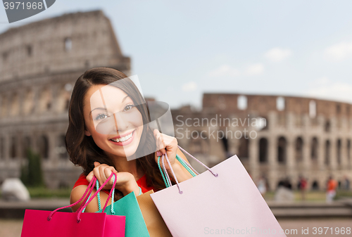 Image of young happy woman with shopping bags over coliseum