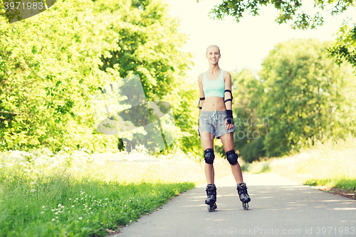 Image of happy young woman in rollerblades riding outdoors