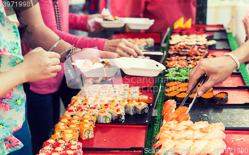 Image of close up of hands with tongs taking sushi