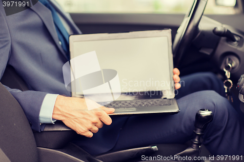 Image of close up of young man with laptop driving car