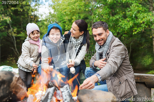 Image of happy family roasting marshmallow over campfire