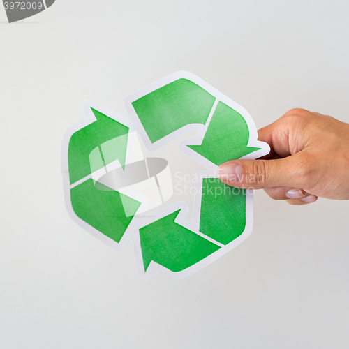 Image of close up of hand holding green recycle symbol