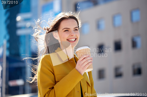 Image of happy young woman drinking coffee on city street