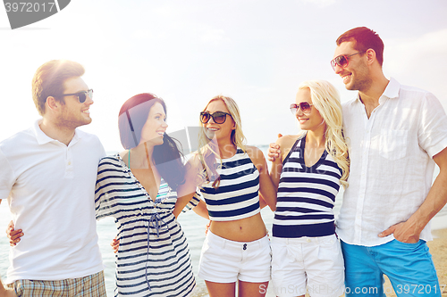 Image of smiling friends in sunglasses talking on beach