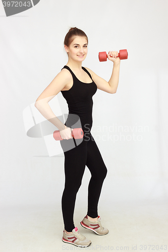 Image of Portrait of young beautiful woman making physical exercises with dumbbells