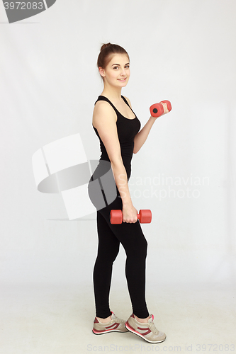 Image of Portrait of young beautiful woman making physical exercises with dumbbells