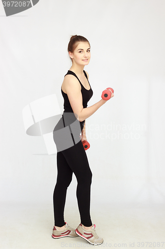 Image of Portrait of young beautiful woman making physical exercises with dumbbells