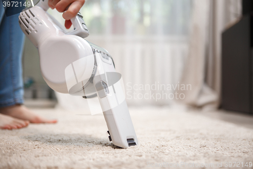 Image of Woman cleaning carpet wireless rechargeable vacuum cleaner