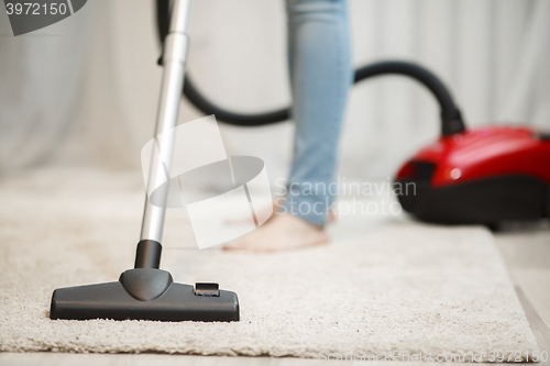 Image of Woman cleaning carpet with vacuum cleaner