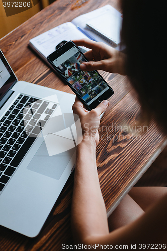 Image of Woman working on computer and looking at the phone