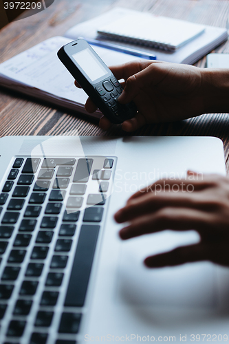 Image of Woman working on computer and looking at the phone