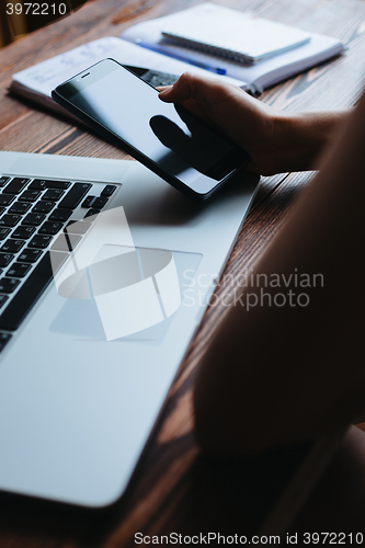 Image of Woman working on computer and looking at the phone