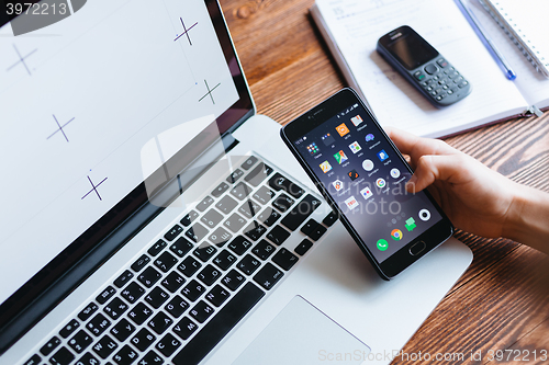 Image of Woman working on computer and looking at the phone