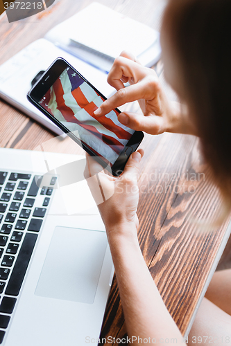 Image of Woman working on computer and looking at the phone