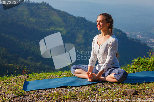 Image of Sporty fit woman practices yoga asana Baddha Konasana outdoors